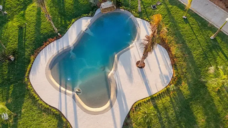 Aerial view of a freeform beach pool set into a green lawn